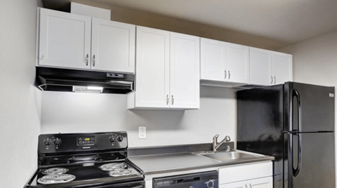 a kitchen with white cabinets and black appliances and a refrigerator